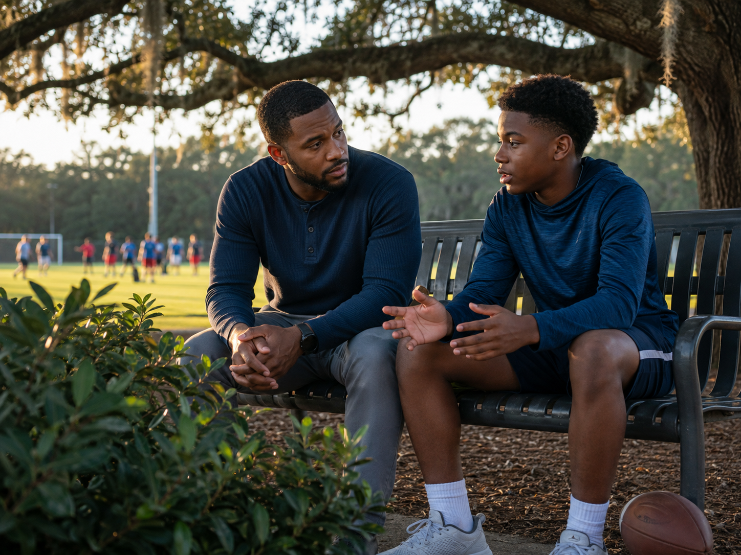 A mentor talking one-on-one with a teen on a park bench